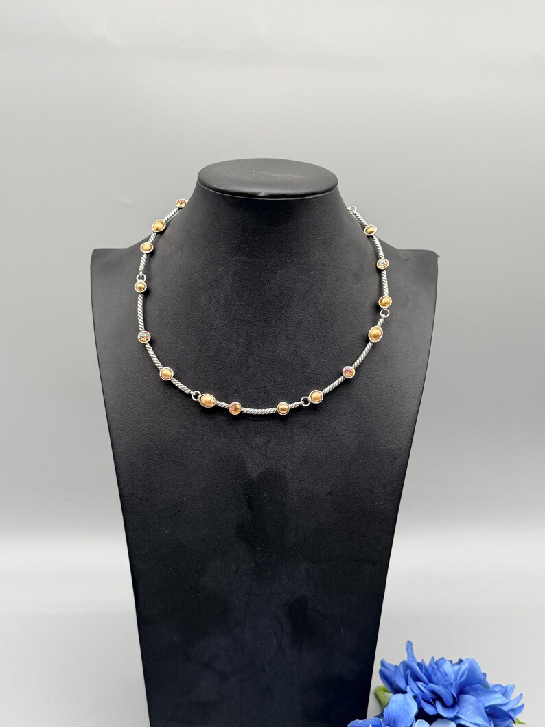 May include: A necklace featuring a twisted silver-tone metal chain interspersed with small, round, gold-tone metal beads and circular accents. The design includes evenly spaced metallic elements along the entire length of the cable-style chain.