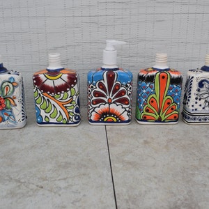 May include: Five ceramic soap dispensers with colorful floral designs. The dispensers are white with blue, green, orange, and red accents.