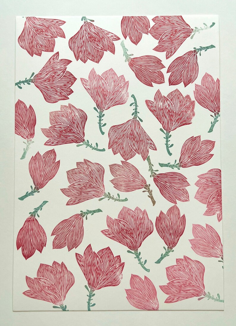 May include: A white background with a repeating pattern of pink magnolia flowers with green stems. The flowers are stylized and have a line drawing aesthetic.