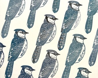 May include: A repeating pattern of blue jays with black eyes and beaks. The birds are arranged in a diagonal pattern on a white background.