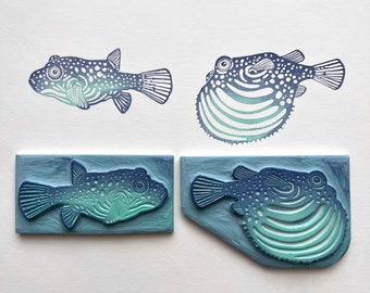 May include: Four rubber stamps featuring a blue and green patterned pufferfish design. Two stamps are mounted on wooden blocks, and two are unmounted.