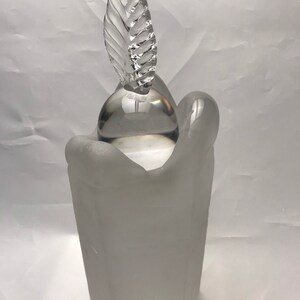 Puede incluir: Un portavelas de vidrio esmerilado con un orbe de vidrio transparente y un remate en forma de hoja.