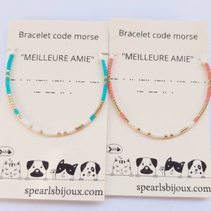 Peut inclure: Deux bracelets avec la phrase "MEILLEURE AMIE" en code morse. Les bracelets sont faits de perles blanches, dorées et turquoise sur l'un et de perles blanches, dorées et corail sur l'autre. Les bracelets sont présentés sur des cartes avec un chat et un chien de dessin animé.