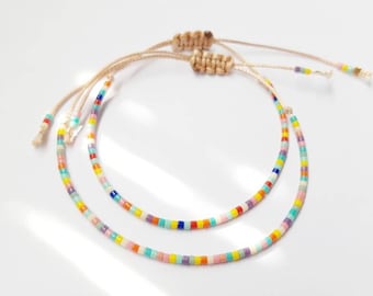 May include: Two colorful beaded bracelets with a rainbow of colors on a white background.