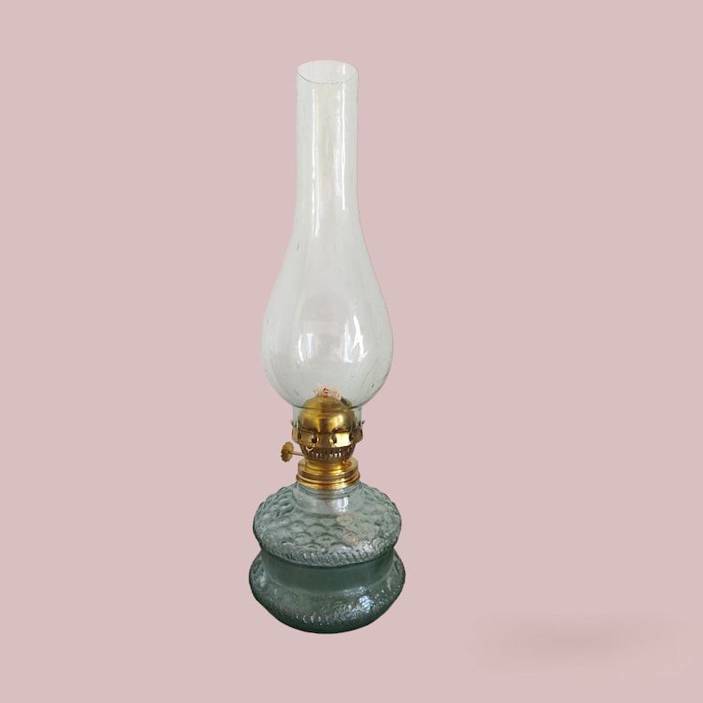 May include: A clear glass oil lamp with a textured green glass base and a brass top.
