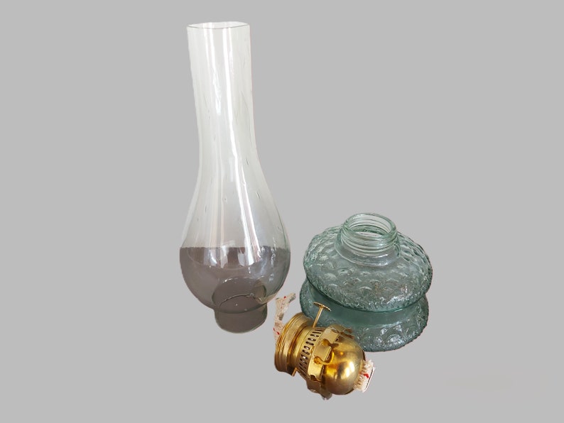 May include: A set of three glass lamp parts, including a clear glass chimney, a green glass globe with a textured surface, and a brass burner.