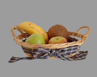 May include: A wicker basket with a blue and white checkered ribbon, filled with a coconut, two green apples, and two yellow bananas.