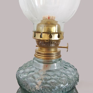 May include: A vintage oil lamp with a clear glass globe and a brass burner. The lamp has a textured green glass base.