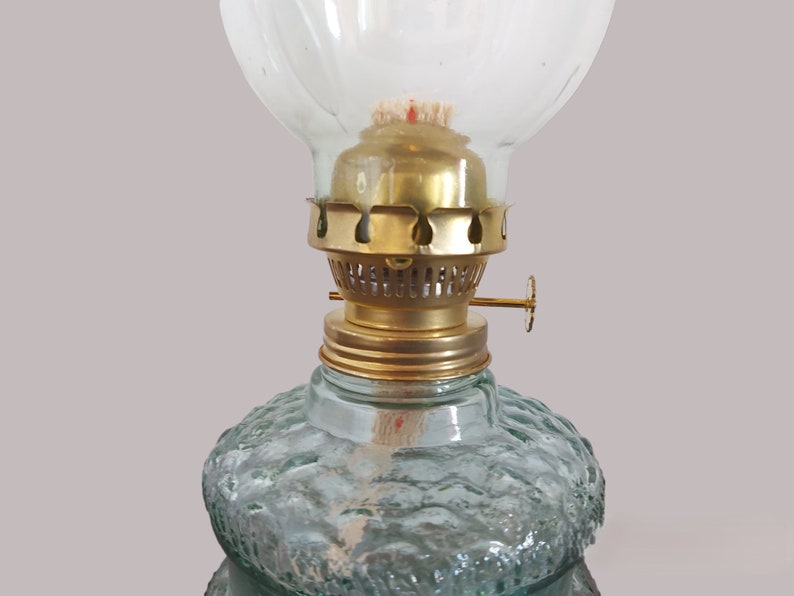 May include: A vintage oil lamp with a clear glass globe and a brass burner. The lamp has a textured green glass base.