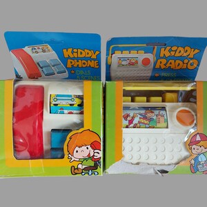 May include: Two vintage toy boxes, one labeled "Kiddy Phone" and the other "Kiddy Radio". Both boxes feature colorful illustrations of children playing with the toys.