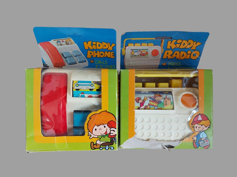 May include: Two vintage toy boxes, one labeled "Kiddy Phone" and the other "Kiddy Radio". Both boxes feature colorful illustrations of children playing with the toys.