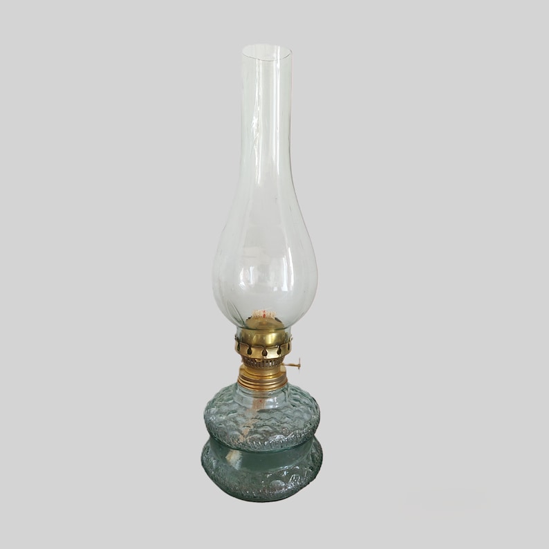 May include: A clear glass oil lamp with a textured glass base and a brass wick holder.
