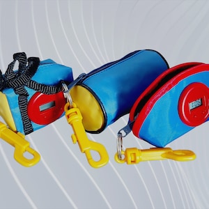 Puede incluir: Tres bolsas azules con cremallera, acentos amarillos y ribetes rojos. Cada bolsa tiene un pequeño temporizador digital unido a un clip amarillo. Las bolsas están unidas a llaveros amarillos.