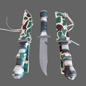 以下が含まれることがあります： 迷彩柄のナイフ3本。黒いハンドルと銀色の刃。ハンドルの先端に懐中電灯機能付き。