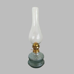 May include: A clear glass oil lamp with a textured glass base and a brass wick holder.
