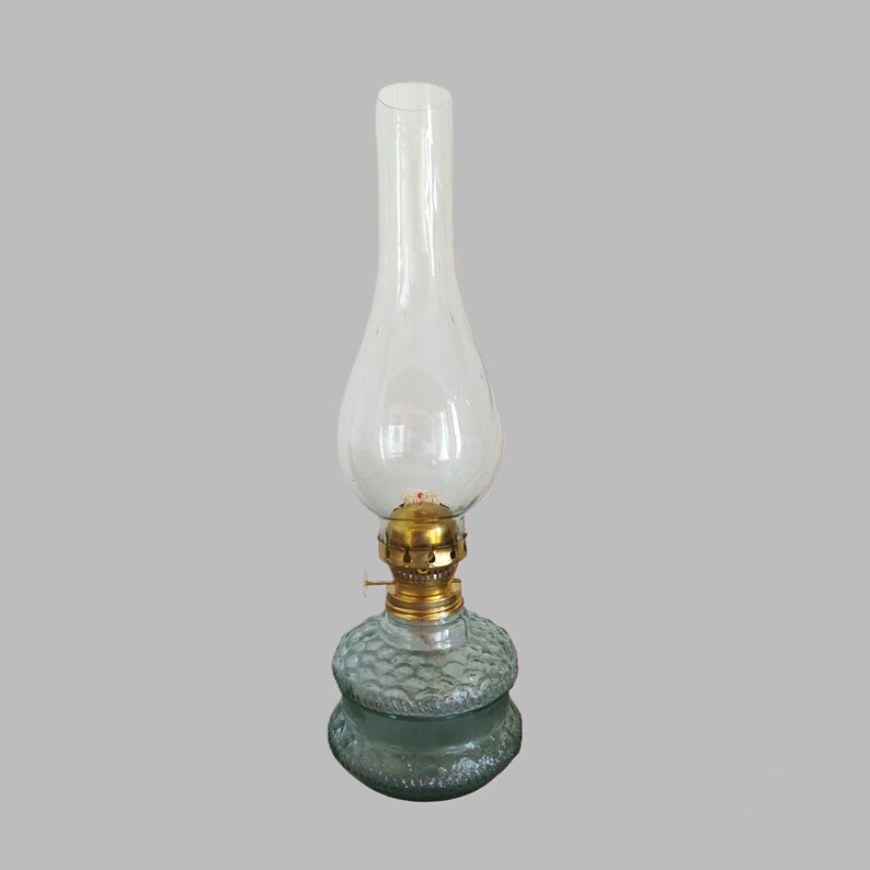 May include: A clear glass oil lamp with a textured glass base and a brass wick holder.