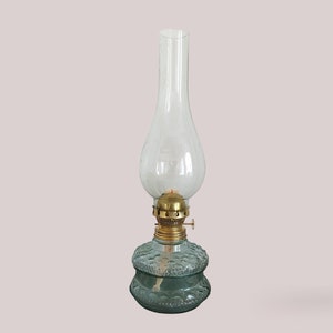 May include: A clear glass oil lamp with a textured green base and a brass top.