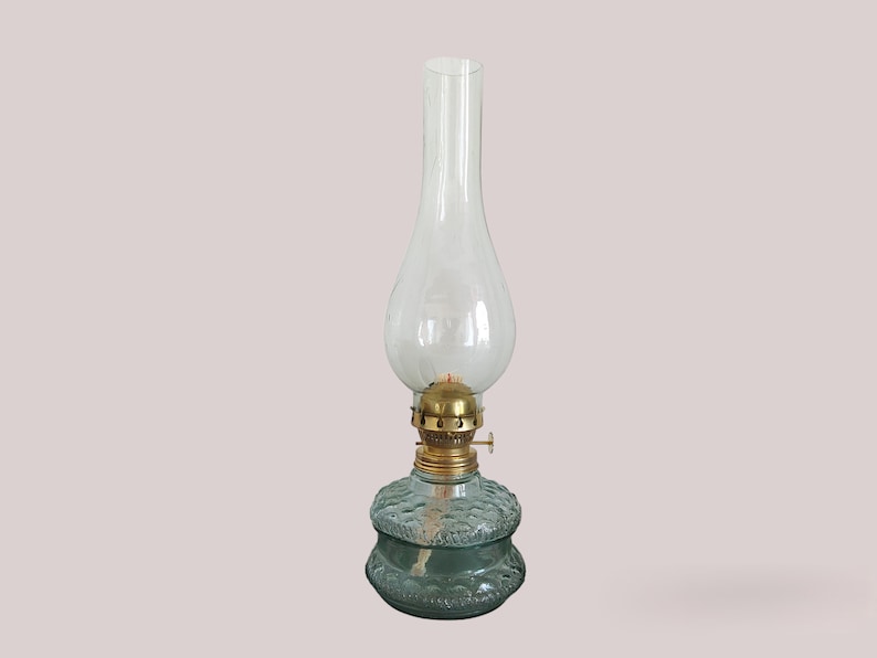 May include: A clear glass oil lamp with a textured green base and a brass top.