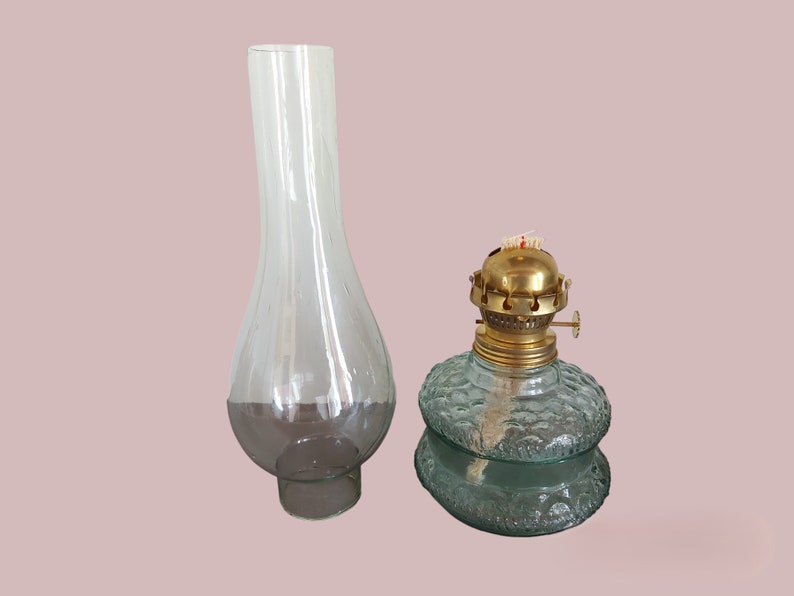 May include: A clear glass oil lamp chimney and a green glass oil lamp with a brass top and wick.