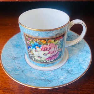Op de afbeelding: Een blauwe en witte porseleinen theekop en schotelset met een bloemenmotief. De kop heeft een gouden rand en de schotel heeft een marmerblauw ontwerp.