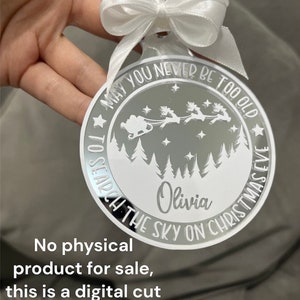 以下が含まれることがあります： サンタクロースがトナカイに乗ったそりで森の上を飛んでいるクリスマスのシーンが白く描かれた、丸くて白い鏡面仕上げのオーナメント。オーナメントの外側には「May you never be too old to search the sky on Christmas Eve」という文字が書かれている。オーナメントの中央には「Olivia」という名前が書かれている。