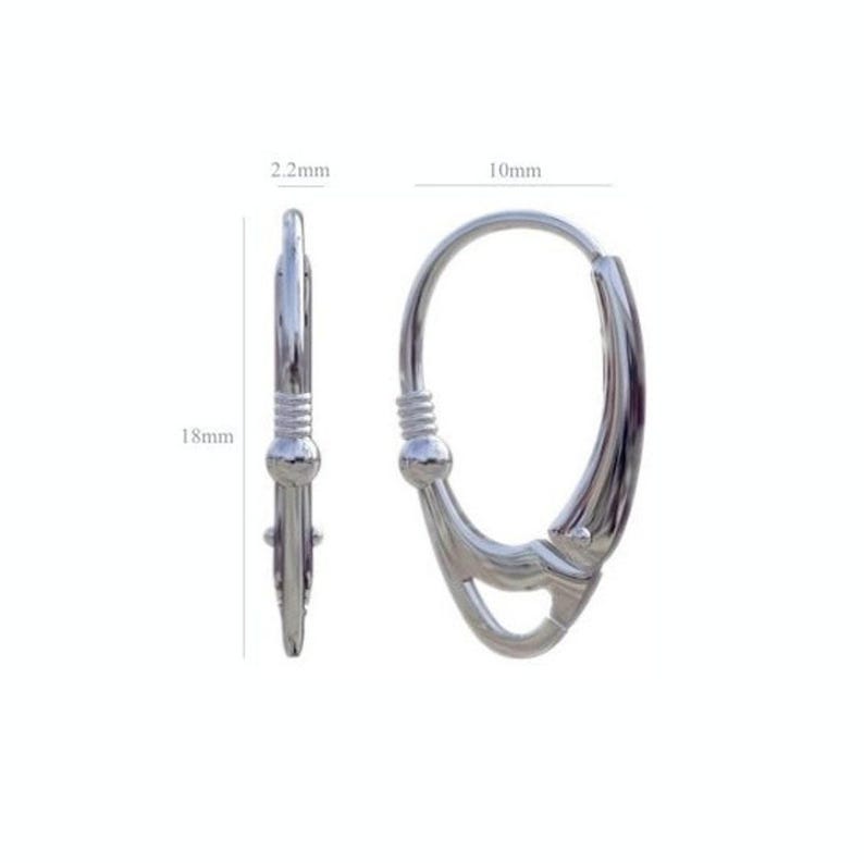 Sterling silver leverback earrings shown in an open position on a wooden surface.