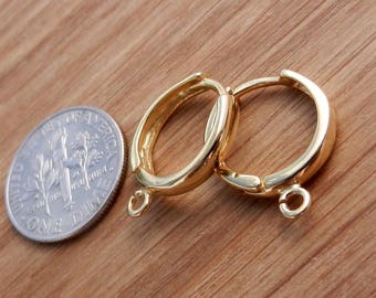 以下が含まれることがあります： 2つの金色のフープイヤリング。それぞれにジャンプリングが付いています。イヤリングは10セント硬貨くらいの大きさです。