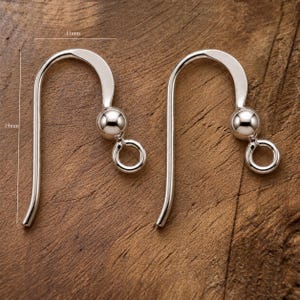 May include: Two silver-toned earring hooks with a smooth, curved design, each featuring a small decorative ball and a circular loop at the base. The hooks measure 11mm in width and 19mm in height as indicated by the visible measurement lines.