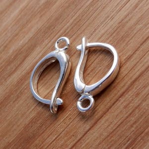 May include: Two silver earring hooks, one with a closed loop and the other with an open loop. The hooks are made of metal and have a shiny finish.