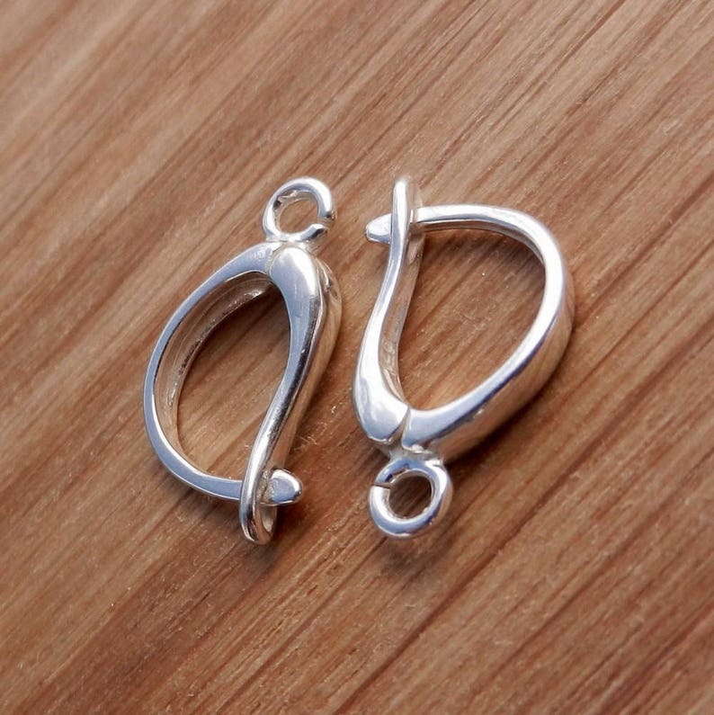 May include: Two silver earring hooks, one with a closed loop and the other with an open loop. The hooks are made of metal and have a shiny finish.