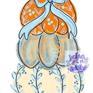 May include: A stack of three pumpkins featuring a brown stem, an orange top pumpkin with white leaf patterns, a central blue-toned pumpkin, and a bottom cream-colored pumpkin with blue leaf designs, accented by a light blue bow and a logo.