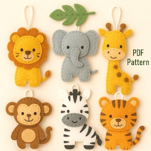 Puede incluir: Adornos de animales de fieltro, incluyendo un león, un elefante, una jirafa, un mono, una cebra y un tigre. Cada adorno es de colores brillantes y tiene un lazo para colgar. También se incluye una hoja verde de fieltro. El texto "PDF Pattern" es visible.