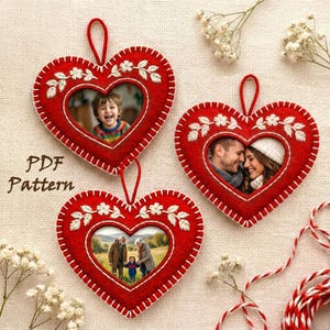 Puede incluir: Tres adornos rojos en forma de corazón con costuras blancas y bordados florales. Cada adorno tiene una foto en su interior. El texto "PDF Pattern" es visible a la izquierda. Ideales para San Valentín u otras ocasiones.