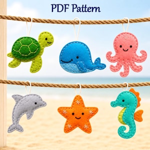 May include: A PDF pattern featuring six felt sea creature ornaments hanging from a rope. The set includes a green turtle, a blue whale, a pink octopus, a gray dolphin, an orange starfish, and a teal seahorse, each with white hanging loops.