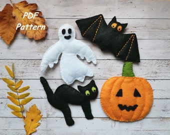 以下が含まれることがあります： フェルト製のハロウィーンの飾り。ゴースト、コウモリ、黒猫、カボチャなどがあります。飾りは白い木製の背景の上にあります。PDFパターン。