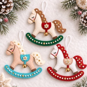 May include: Three felt rocking horse ornaments with white hanging loops. Each horse features stitched details, a small gold bell, and is decorated with small white pearls and gold sequins. The rockers are green, blue, and red with star accents.