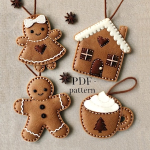 May include: Four felt Christmas ornaments: a gingerbread person, a gingerbread house, a gingerbread girl, and a gingerbread mug with whipped cream. The ornaments are brown, white, and red. The text "PDF - pattern" is printed on the image.