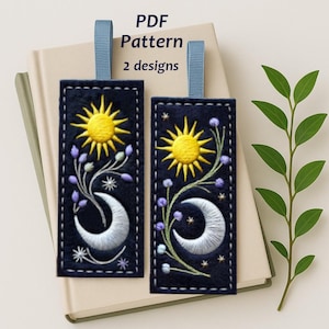 May include: Two navy blue embroidered bookmarks with a sun, moon, and floral design. The bookmarks have a blue ribbon attached. The text "PDF Pattern 2 designs" is visible at the top.