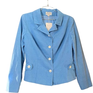 May include: A light blue blazer with a classic collar, three buttons, and two front pockets. The blazer is hanging on a metal hanger. A tag is attached to the blazer.