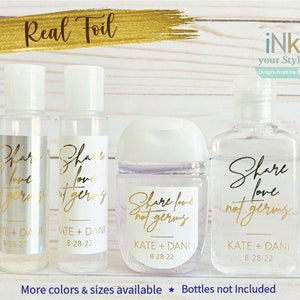 May include: Four clear plastic bottles with labels that say "Share love not germs" in gold foil lettering. The labels also include the names "Kate + Dani" and the date "8-28-22". One bottle has a silver label. The bottles are on a white wood background.