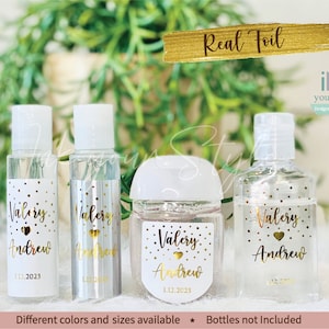May include: Four clear plastic bottles with gold foil labels. The labels have a white polka dot background and gold text that reads "Valery Andrew" and "1.12.2023". The bottles are arranged in a row on a white surface. Real Foil iNk your Style Designs from the.