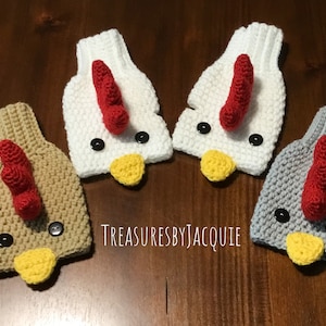 May include: Four pairs of crocheted chicken finger puppets. Two pairs are tan, one pair is white, and one pair is gray. Each puppet has a red comb, black eyes, a yellow beak, and a white button on the front.