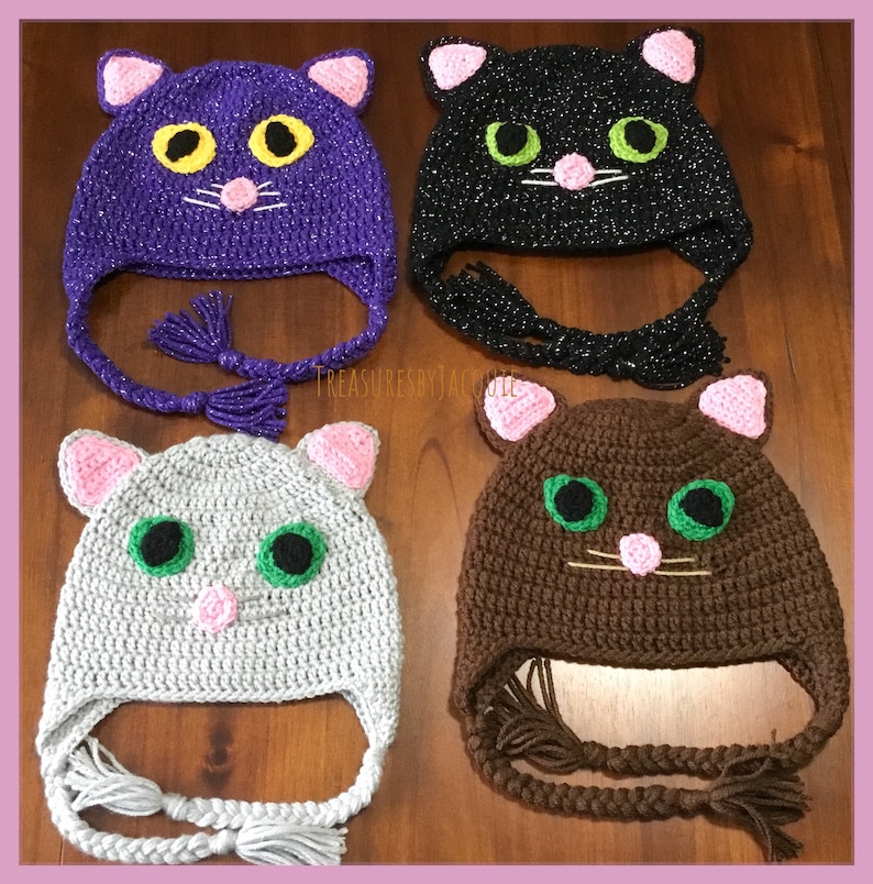 Puede incluir: Cuatro gorros de ganchillo con forma de gato en diferentes colores: morado, negro, gris y marr&oacute;n. Cada gorro tiene una nariz rosa, ojos verdes y un par de orejas rosas. Los gorros tienen lazos largos con borlas.