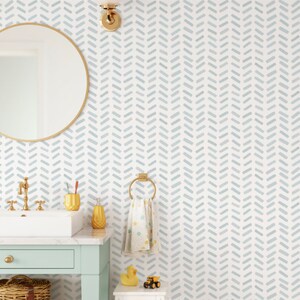 May include: A bathroom scene with a light blue and white chevron patterned wallpaper. A gold-framed mirror, a white sink with gold fixtures, and a mint green vanity are visible. Accessories include a gold soap dispenser, toothbrush holder, and a towel ring.