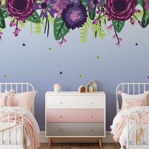 May include: Two white twin beds with pink bedding and a white dresser with pink, grey, and white drawers. The wall behind the beds is painted a light purple and features a floral mural with purple, pink, and green flowers.