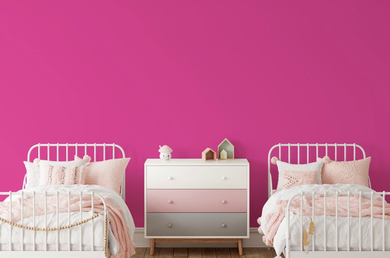 May include: A bedroom scene with two white metal frame beds, each with pink and white bedding. A white, pink, and gray dresser sits between the beds. Decorative items include a mushroom-shaped night light and wooden houses.
