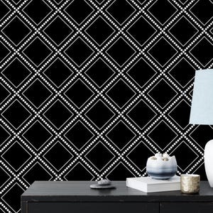 May include: Black and white geometric wallpaper with a white dotted diamond pattern. A white lamp with a light blue lampshade sits on a black table with a book and a decorative object.