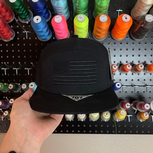 May include: Black baseball cap with an embroidered American flag design and the text "PREMIUM QUALITY HEADWEAR 707 GAMES" on the front.