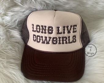 Op de afbeelding: Een bruine en beige trucker-pet met de tekst "Long Live Cowgirls" geborduurd in bruin op de voorkant. De pet heeft een bruin gaas achterkant en een bruine klep.