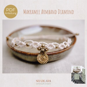 May include: White macrame bracelet with gold beads and a gold charm. The bracelet is on a brown ceramic dish. The image also includes a PDF download icon and the text "Makramee Armband Diamond".